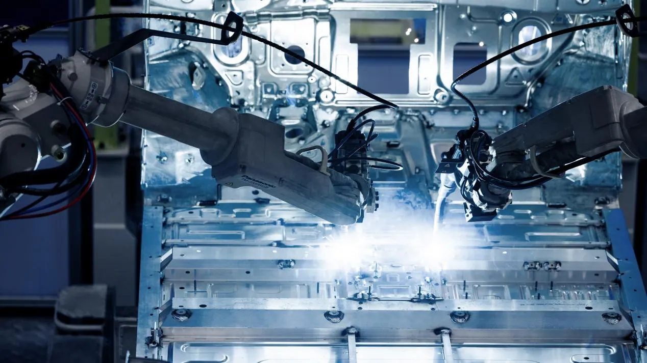 Bras robotisés travaillant sur une carrosserie métallique dans une usine