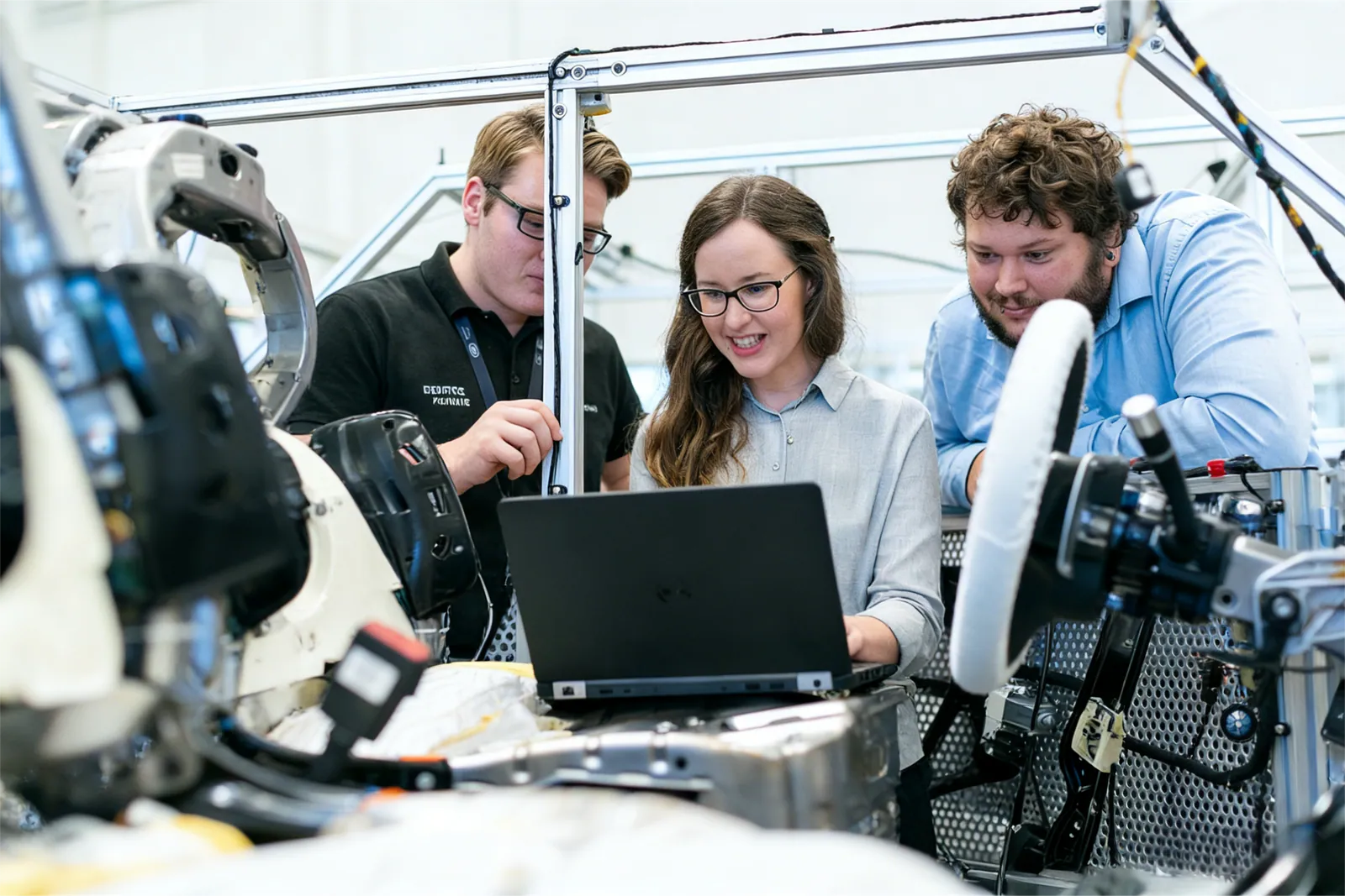 Trois ingénieurs travaillant ensemble sur un véhicule dans un atelier technique